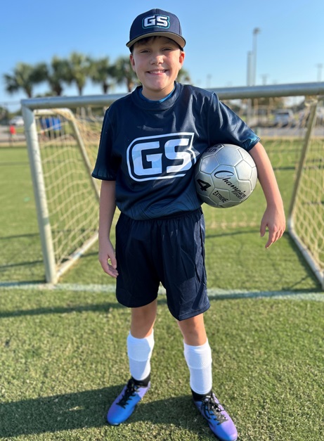 Carson in a soccer uniform standing in front of the goal.